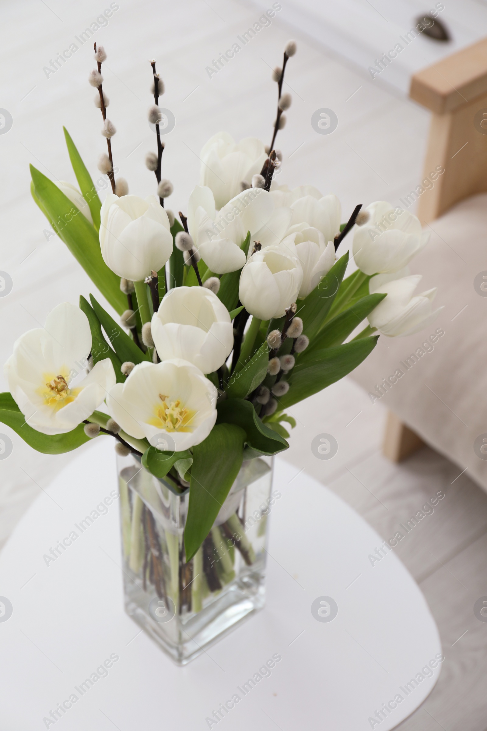 Photo of Beautiful bouquet of willow branches and tulips in vase on table indoors, above view