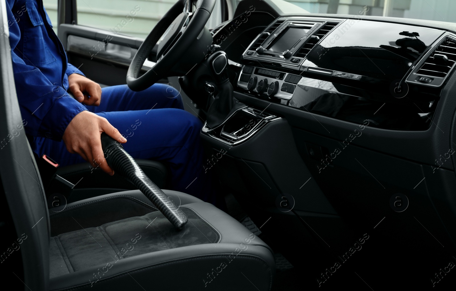 Photo of Car wash worker vacuuming automobile seat, closeup