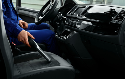 Photo of Car wash worker vacuuming automobile seat, closeup