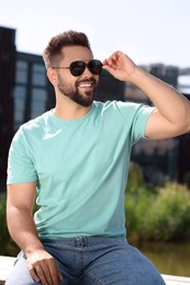 Handsome smiling man in sunglasses outdoors on sunny day