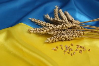 Photo of Ears of wheat and grains on Ukrainian national flag, space for text