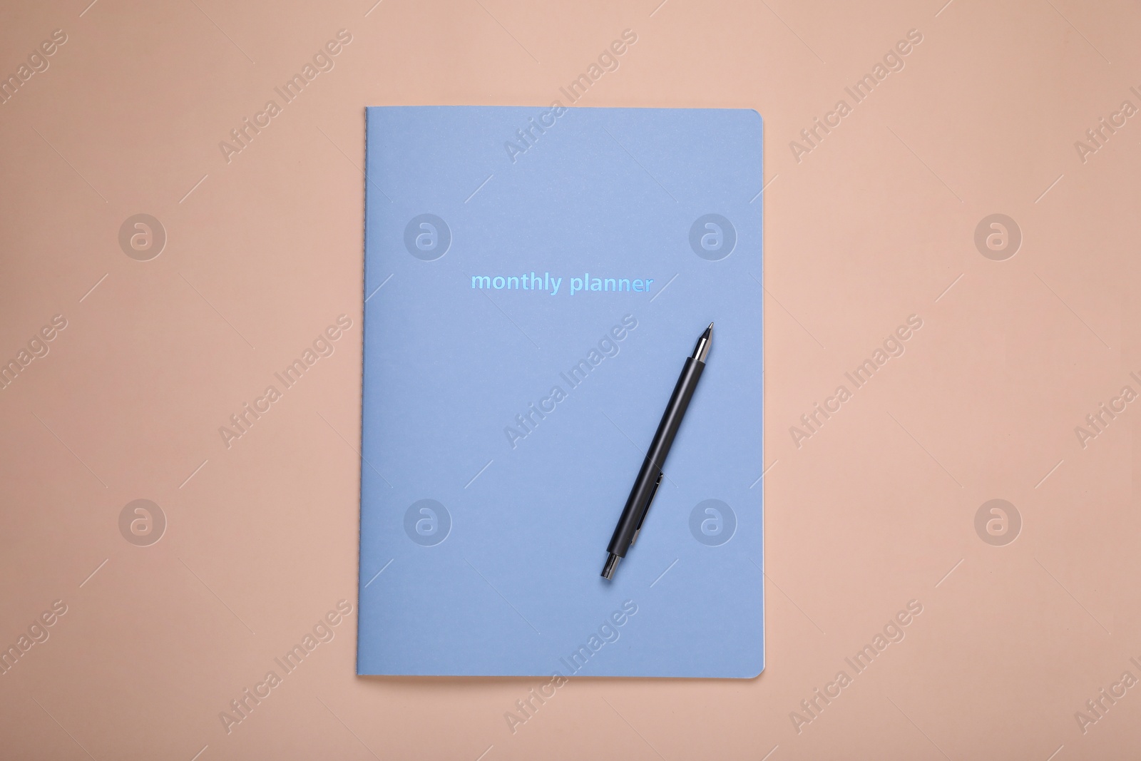 Photo of Monthly planner and pen on beige background, top view