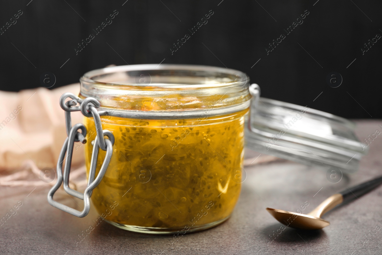 Photo of Jar of delicious gooseberry jam on grey table, closeup