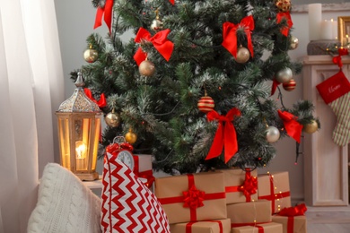 Photo of Decorative lantern on table and Christmas tree with gift boxes in stylish living room interior