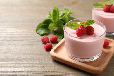 Delicious raspberry mousse with mint on wooden table, space for text