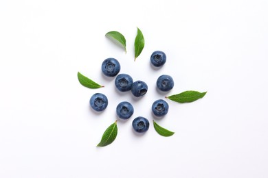 Tasty fresh blueberries with green leaves on white background, flat lay