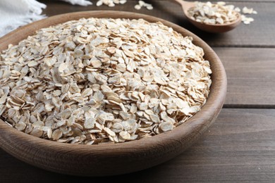 Photo of Raw oatmeal in bowl on wooden table, closeup