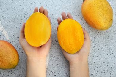 Photo of Woman with halves of ripe mango, top view