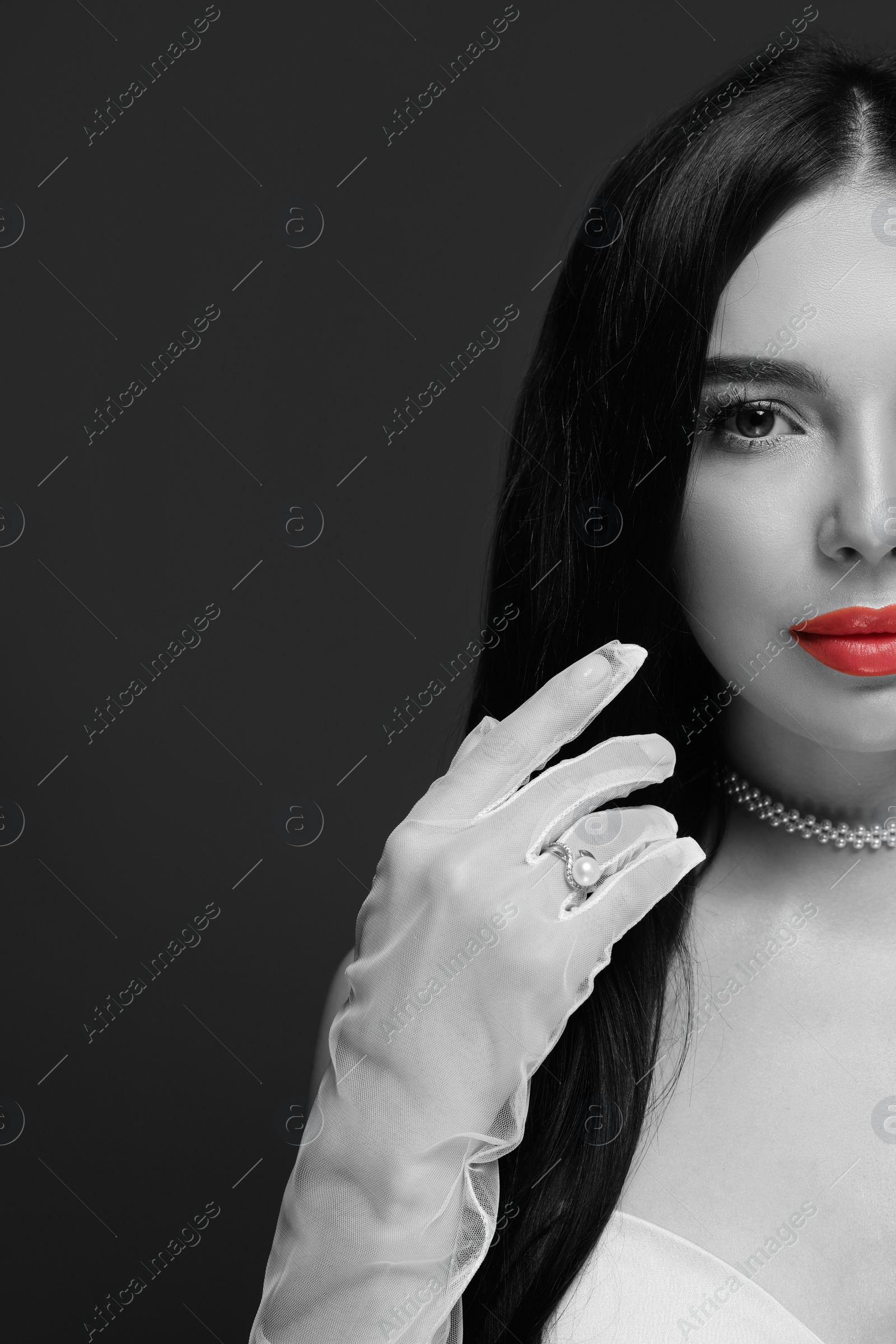 Image of Portrait of beautiful young woman on dark background. Black and white photo with red accent