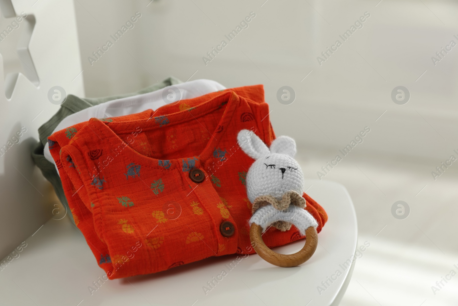 Photo of Baby clothes and toy on chair indoors, closeup. Space for text