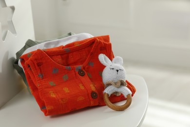 Photo of Baby clothes and toy on chair indoors, closeup. Space for text
