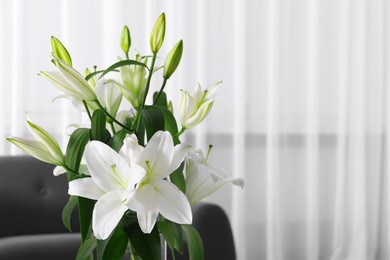 Photo of Beautiful lily flowers in living room, space for text