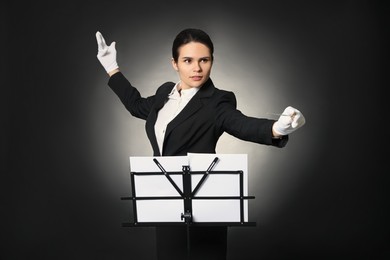 Photo of Professional conductor with baton and note stand on black background