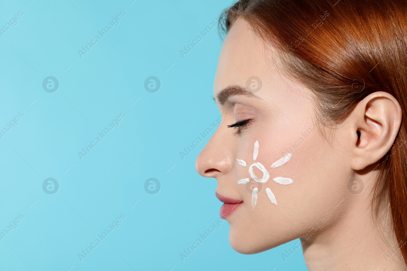 Photo of Beautiful young woman with sun protection cream on her face against light blue background, closeup. Space for text