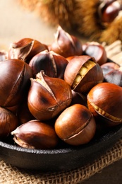 Photo of Tasty roasted edible chestnuts on table, closeup