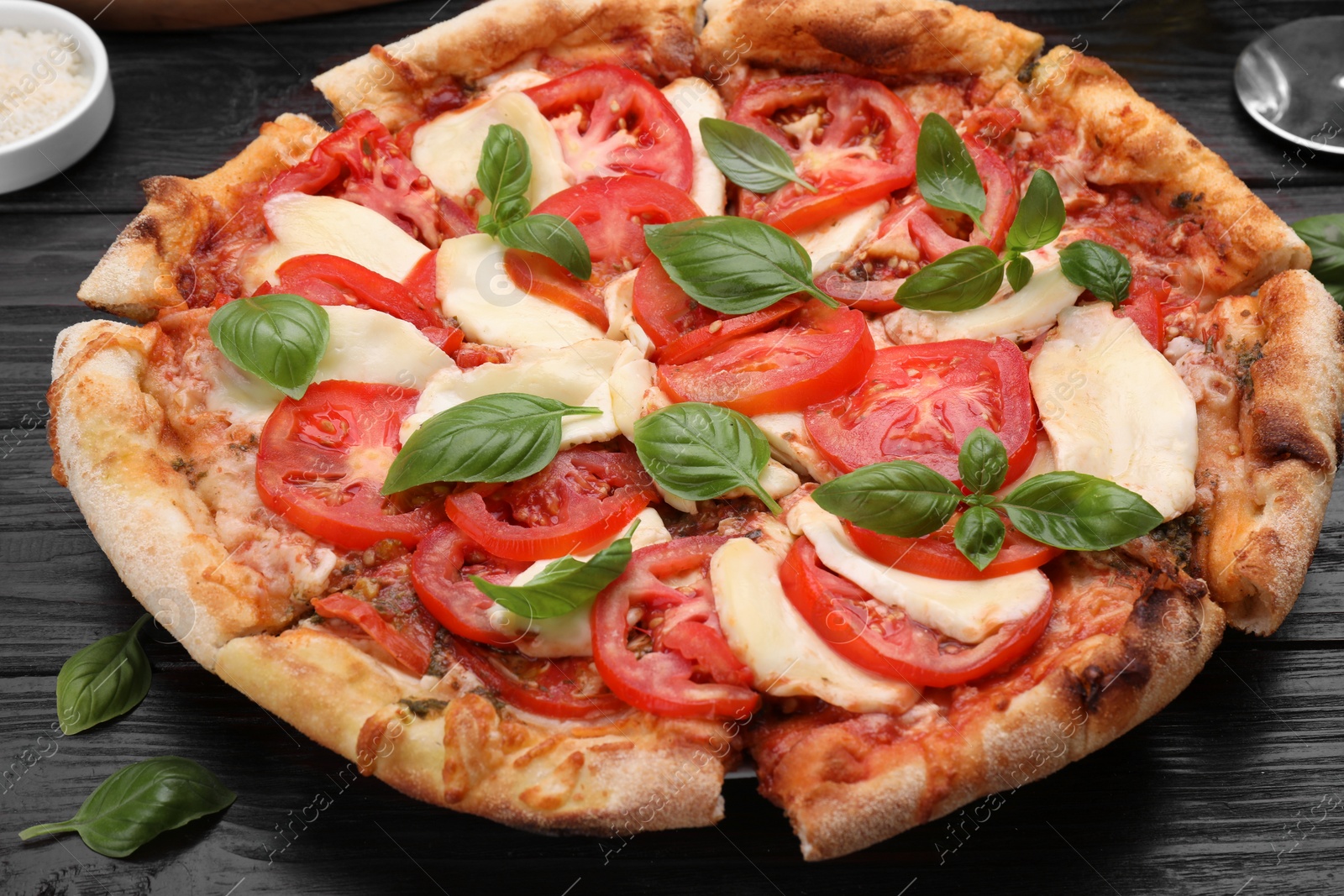 Photo of Delicious Caprese pizza on black wooden table, closeup