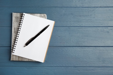 Photo of Notebooks and pen on blue wooden table, top view. Space for text