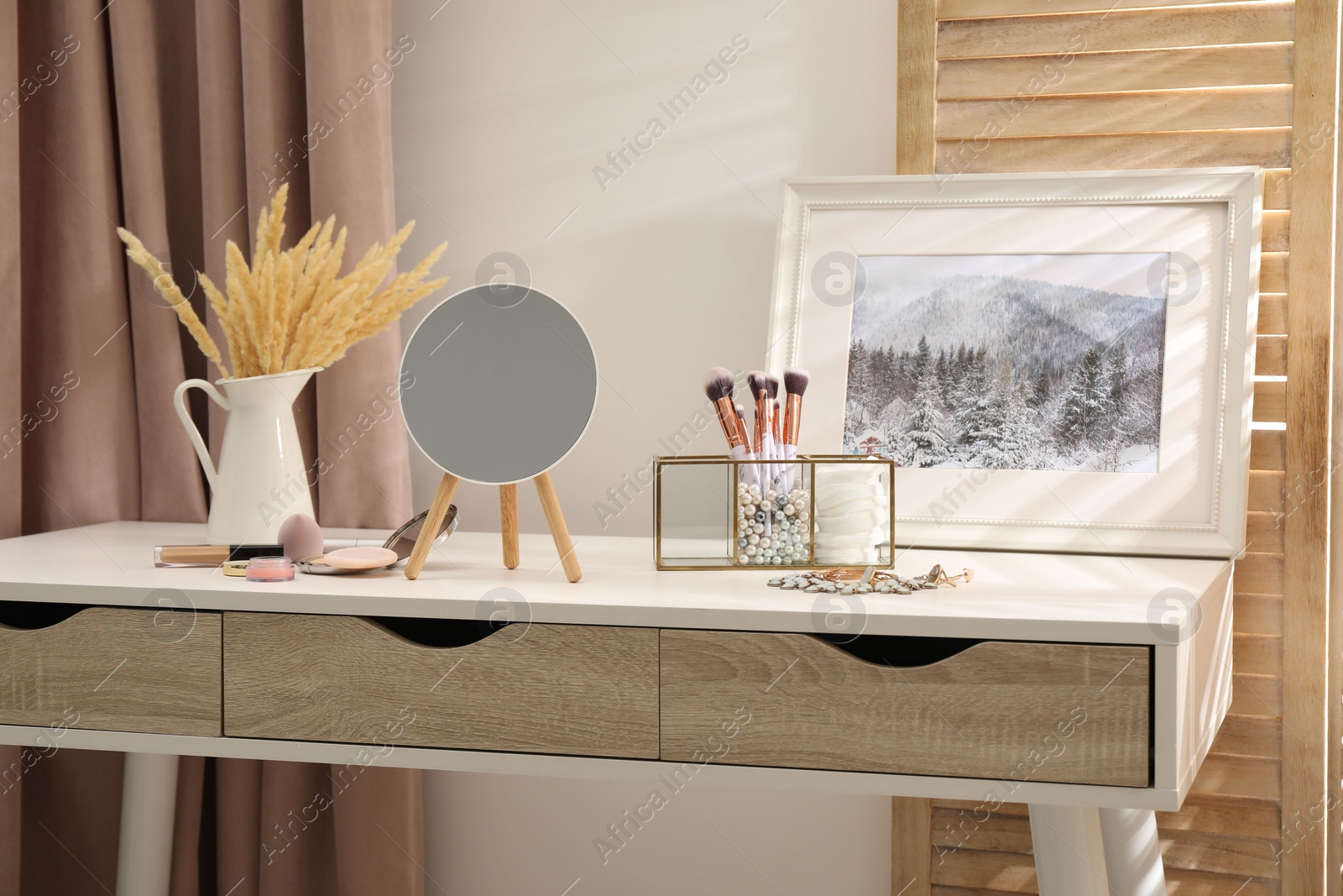 Photo of Dressing table with mirror, cosmetic products and jewelry in makeup room