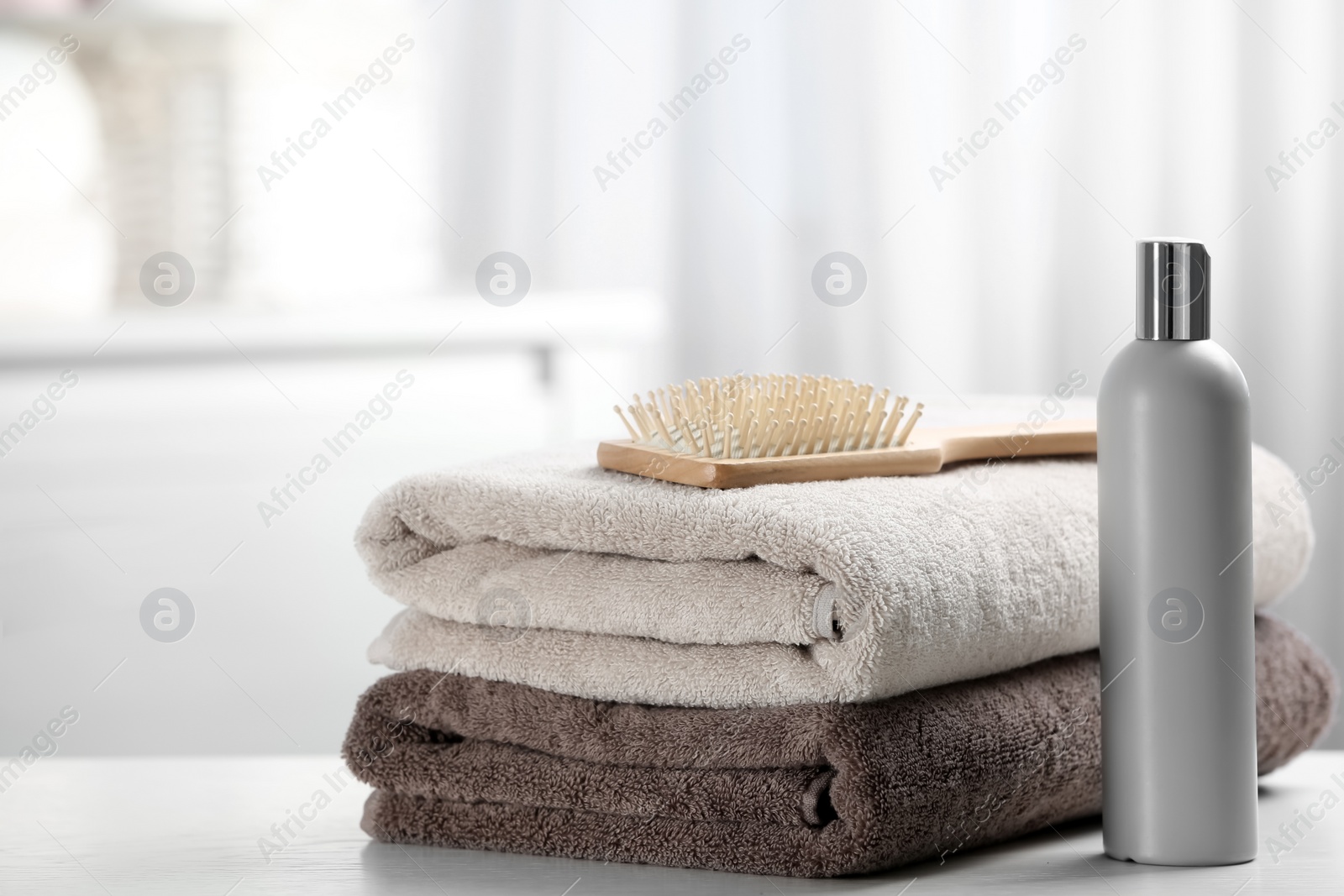 Photo of Towels with hair brush and shampoo on table. Space for text