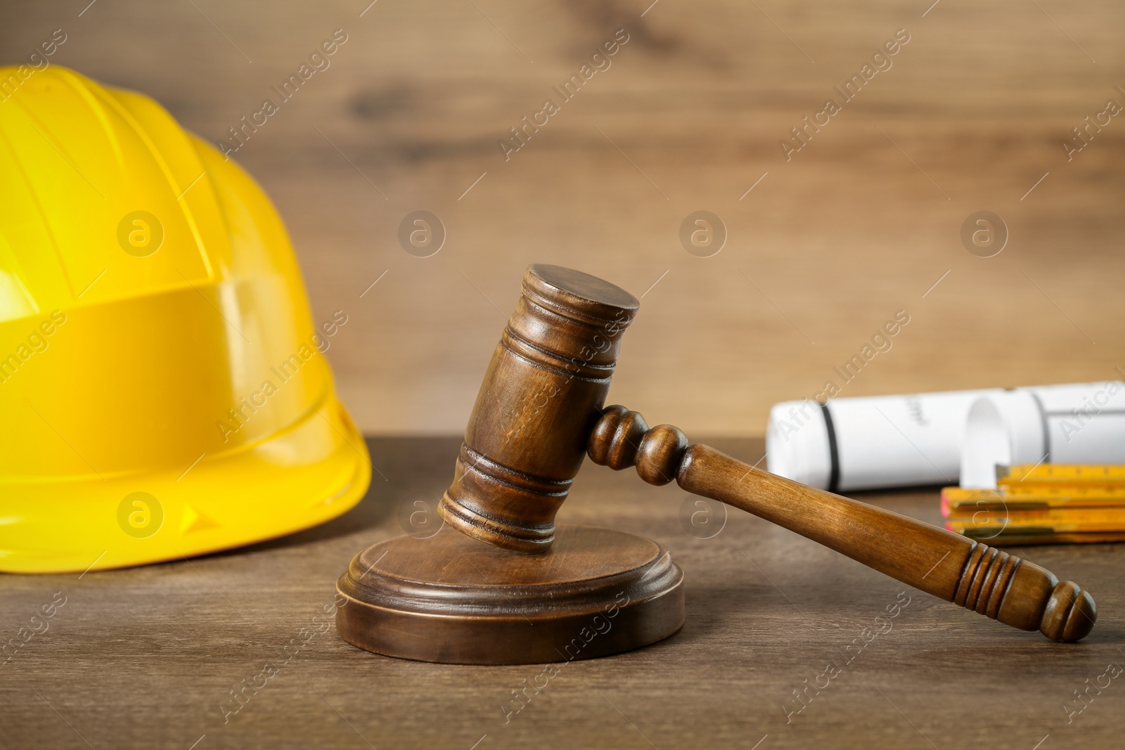 Photo of Construction and land law concepts. Judge gavel, protective helmet with drawings on wooden table