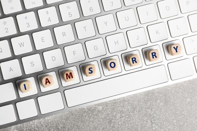 Apology. Phrase I Am Sorry made of wooden cubes and keyboard on grey table, top view