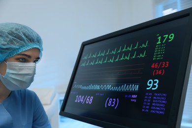 Photo of Nurse near monitor with cardiogram in hospital