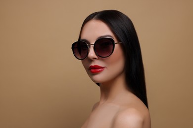 Photo of Attractive woman in fashionable sunglasses against beige background