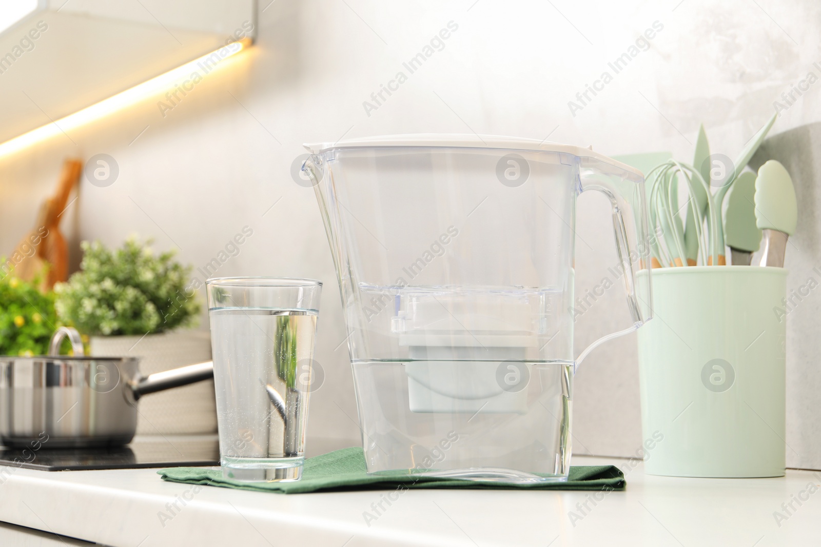 Photo of Water filter jug and glass on white countertop in kitchen