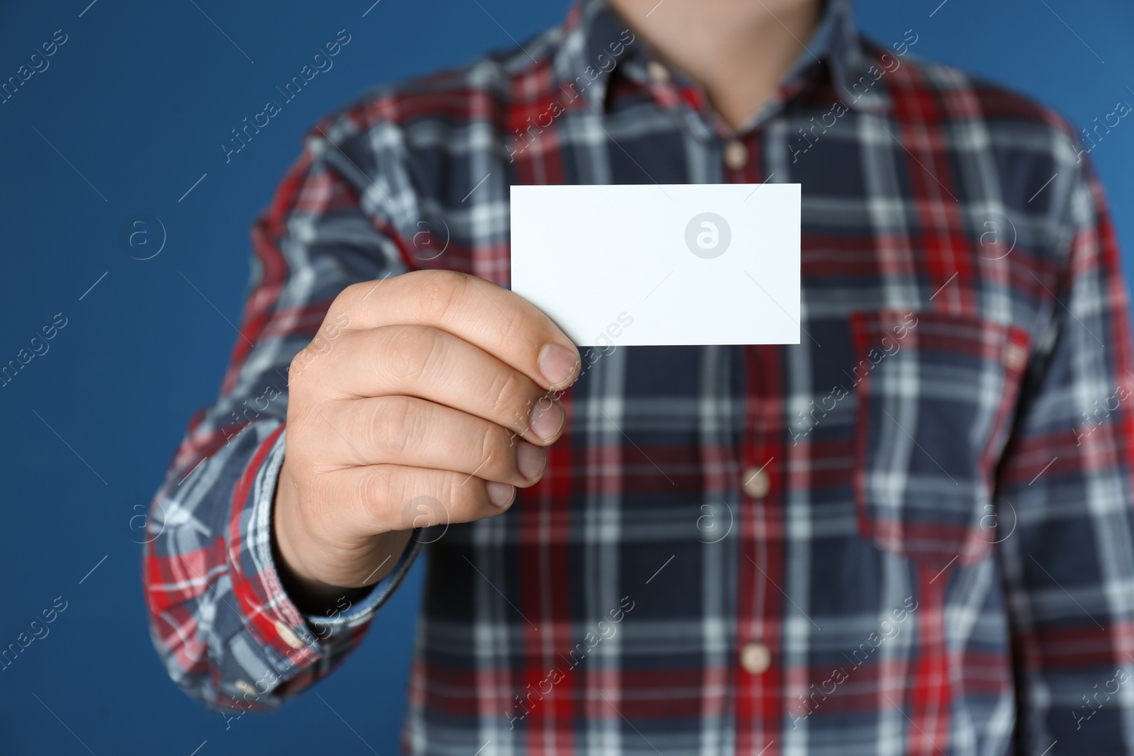 Photo of Man holding white business card on blue  background, closeup
