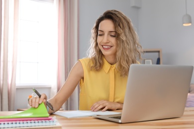 Young woman working with laptop at desk. Home office