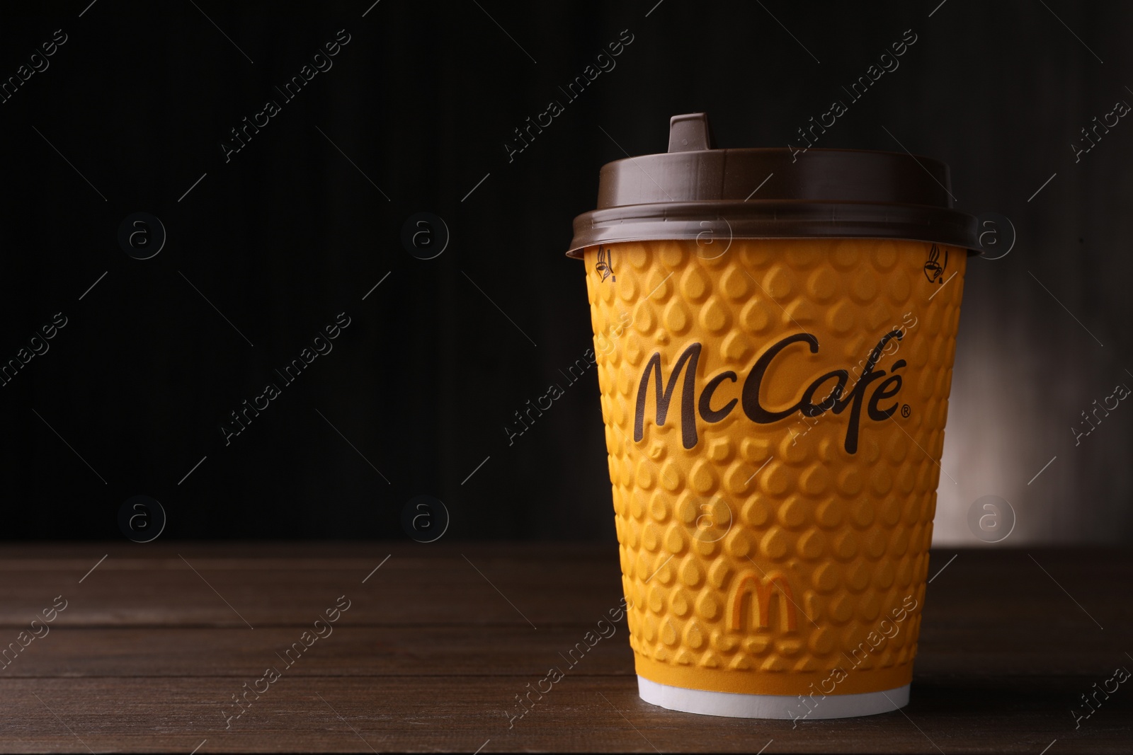 Photo of MYKOLAIV, UKRAINE - AUGUST 12, 2021: Hot McDonald's drink on wooden table. Space for text