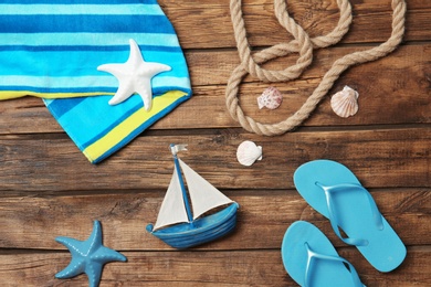 Flat lay composition with small boat and beach objects on wooden background