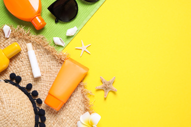 Flat lay composition with sun protection products on yellow background. Space for text