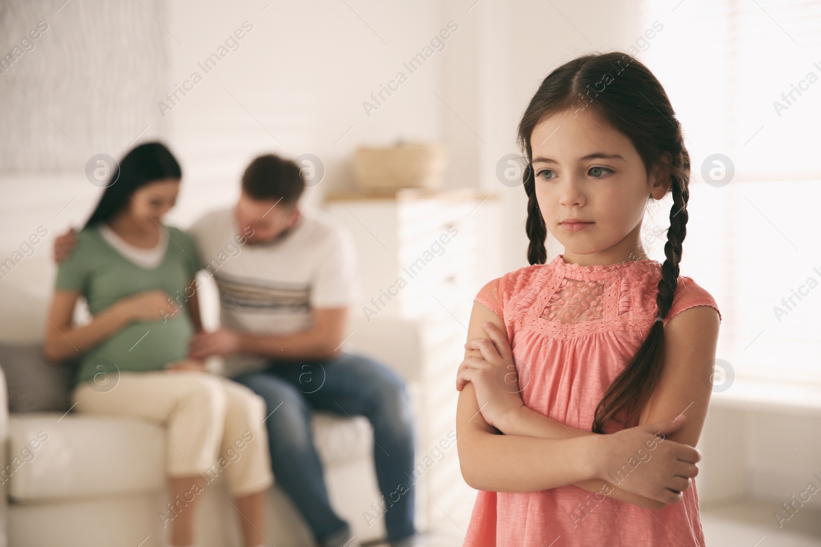 Photo of Unhappy little girl and her father with pregnant mother at home. Feeling jealous towards unborn sibling