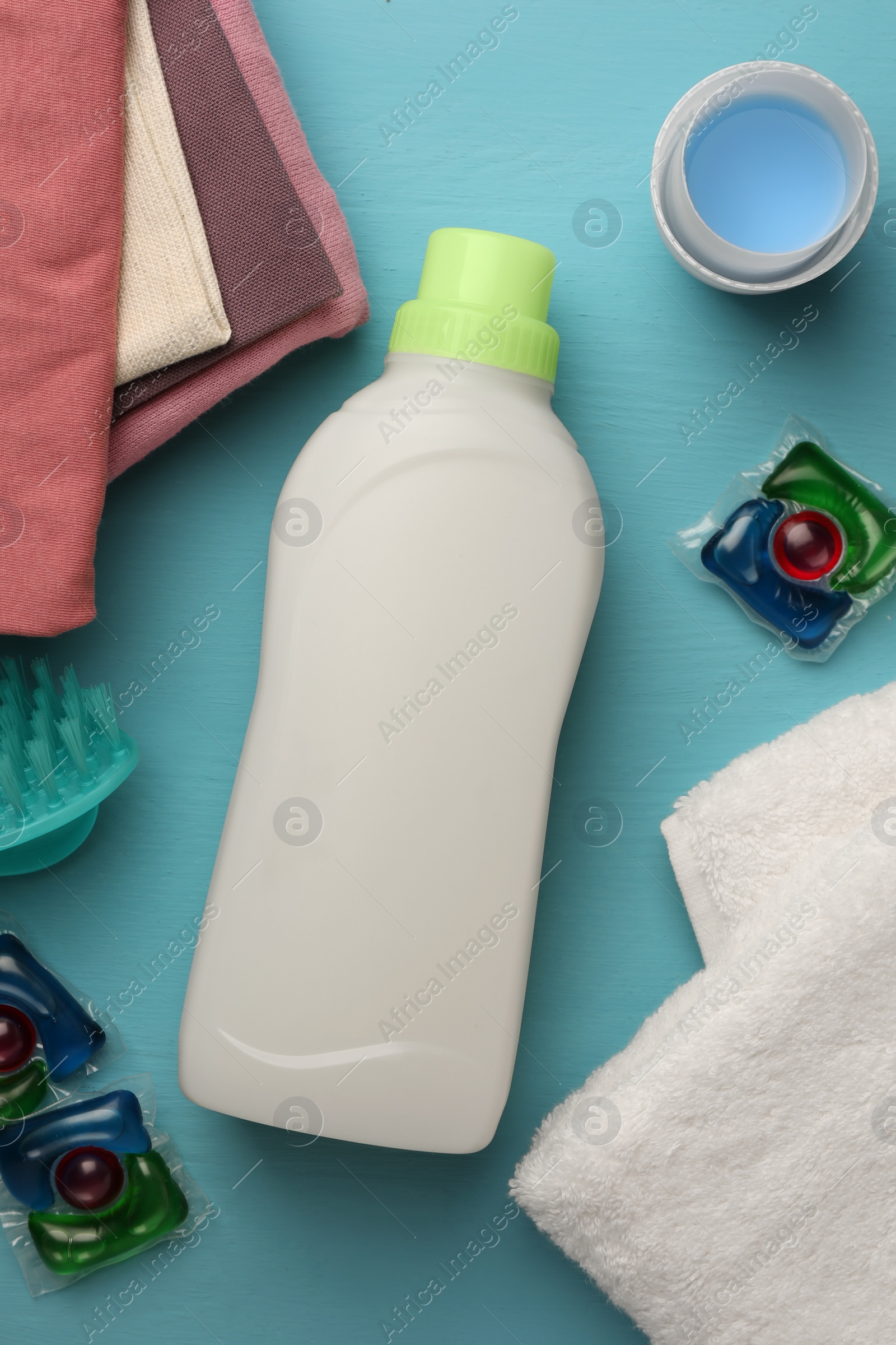 Flat lay composition with bottle of fabric softener on light blue wooden table Photo of Flat lay composition with bottle of fabric softener on light blue wooden table