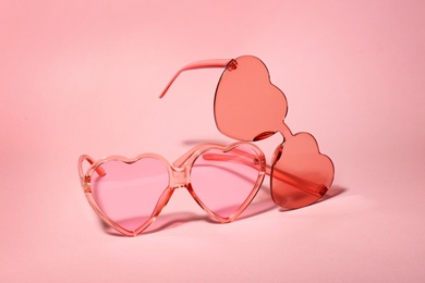 Different stylish heart shaped glasses on color background