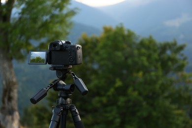 Photo of Taking video with modern camera on tripod in mountains