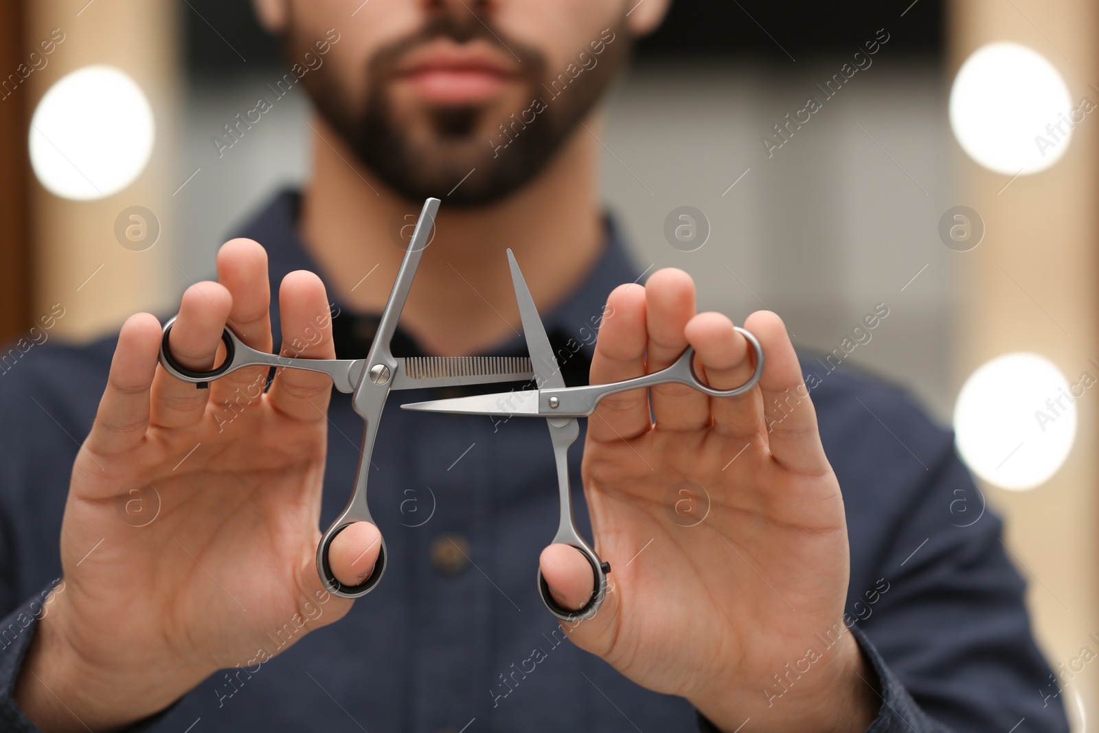 Photo of Hairstylist holding professional scissors in beauty salon, closeup