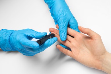 Photo of Diabetes. glucose testing. Doctor using lancet pen on white background, closeup