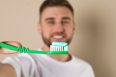 Photo of Young man with brush and toothpaste on color background, selective focus. Teeth care