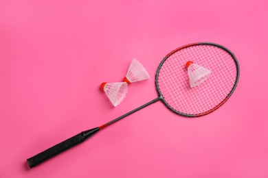 Photo of Racket and shuttlecocks on pink background, flat lay. Badminton equipment