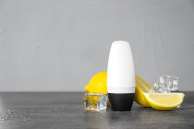 Photo of Deodorant, lemons and ice cubes on dark background