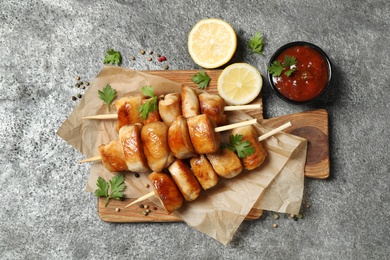 Delicious chicken shish kebabs with parsley and ketchup on grey table, flat lay