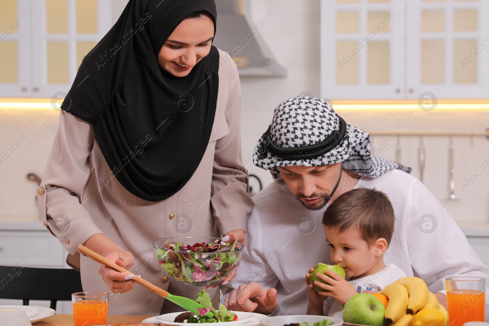 Photo of Happy Muslim family eating together in kitchen