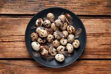 Photo of Plate with quail eggs on wooden table, top view