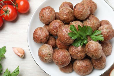 Photo of Tasty cooked meatballs with parsley on white wooden table, flat lay
