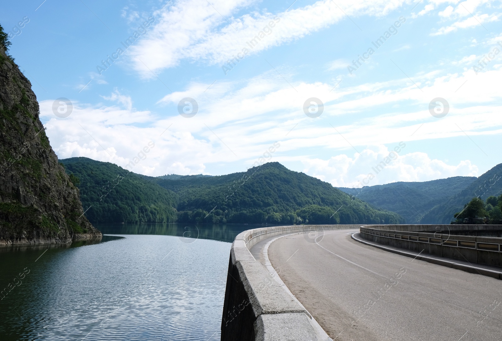 Image of Beautiful lake near hills covered with green forest. View from road