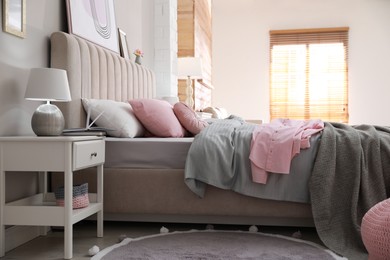 Bed with stylish linens near grey wall in room