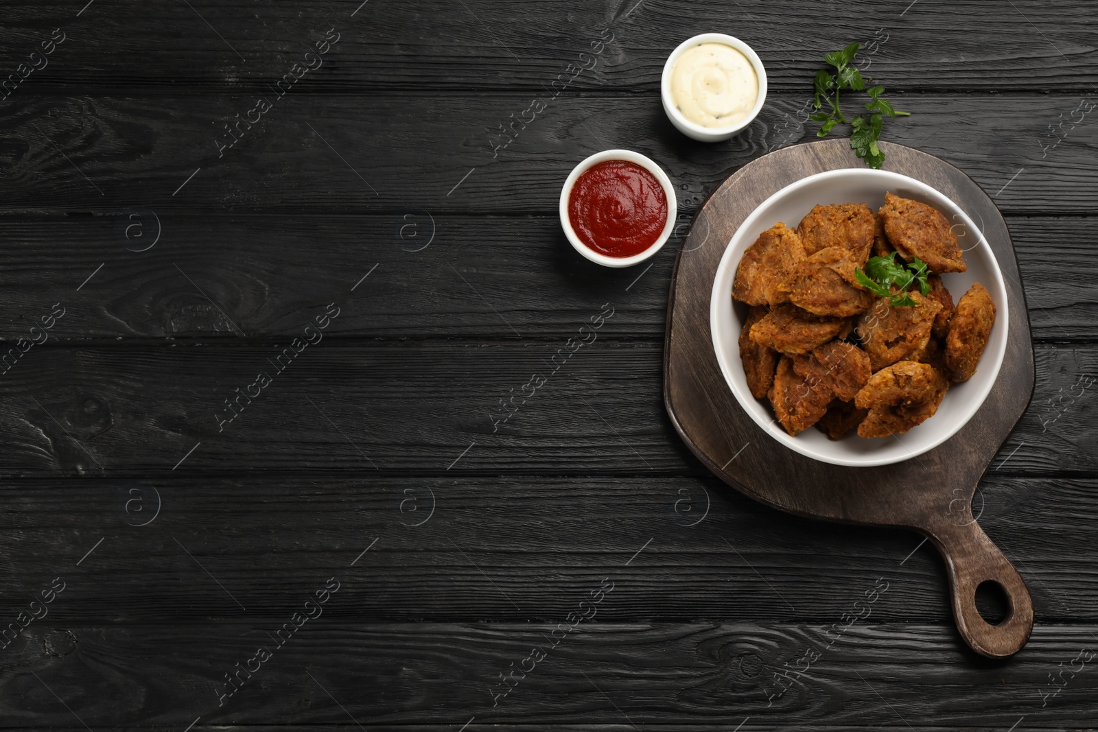 Photo of Cooked soy meat in bowl on black wooden table, flat lay. Space for text