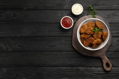 Cooked soy meat in bowl on black wooden table, flat lay. Space for text